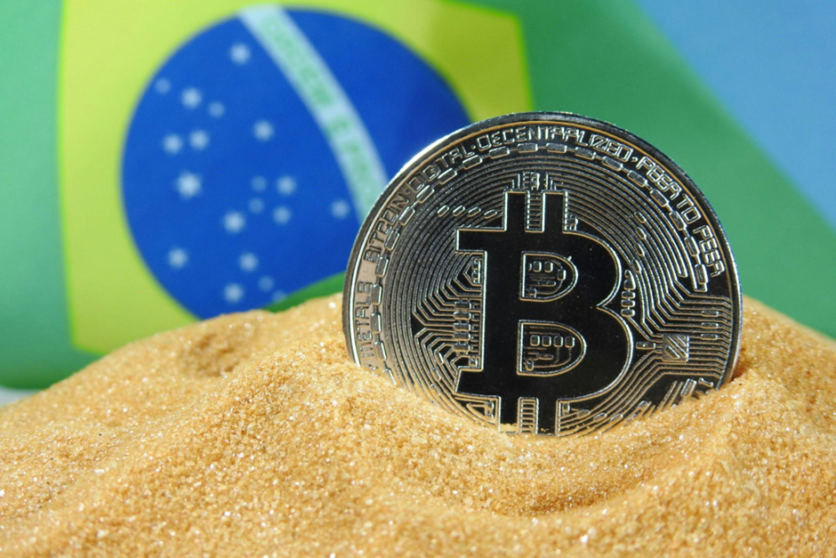 moeda bitcoin na areia com a bandeira do Brasil no fundo moeda bitcoin na areia com a bandeira do Brasil no fundo
